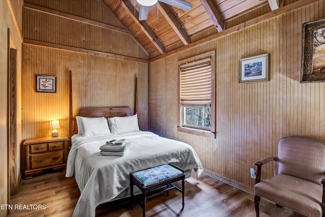 bedroom with wooden walls, lofted ceiling with beams, and wood finished floors