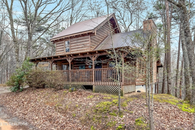 view of front of property with a wooden deck, a chimney, metal roof, and crawl space