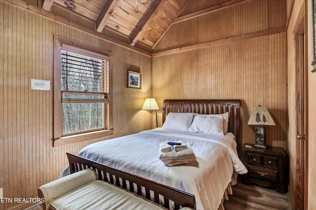 bedroom with wooden walls, wooden ceiling, vaulted ceiling with beams, and wood finished floors