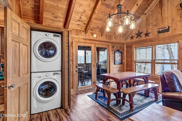 washroom with stacked washer and clothes dryer, wood walls, wood finished floors, wooden ceiling, and a notable chandelier