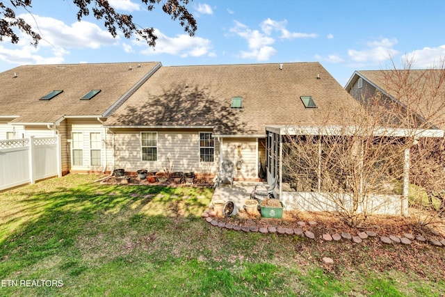 rear view of house featuring a lawn, fence, a shingled roof, and a patio area