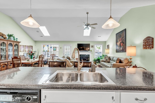 kitchen with white cabinets, open floor plan, a sink, and dishwashing machine
