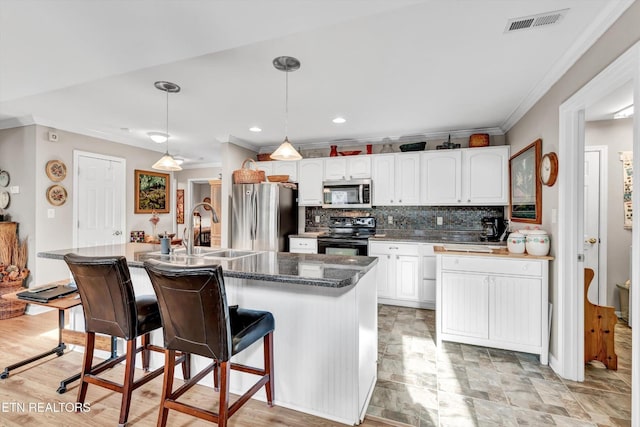 kitchen featuring ornamental molding, a breakfast bar, tasteful backsplash, a sink, and stainless steel appliances