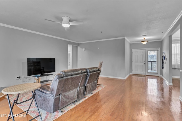 living room featuring light wood-style floors, baseboards, ceiling fan, and ornamental molding