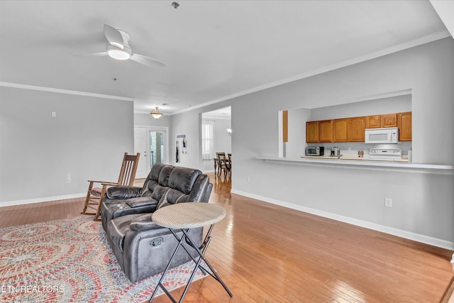 living room with crown molding, light wood finished floors, ceiling fan, and baseboards