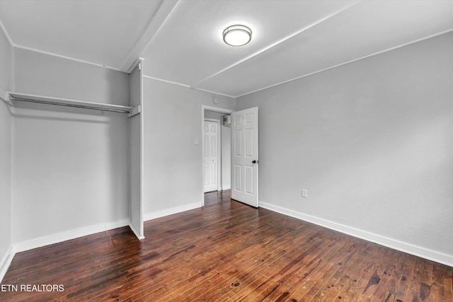 unfurnished bedroom with baseboards, a closet, and hardwood / wood-style floors