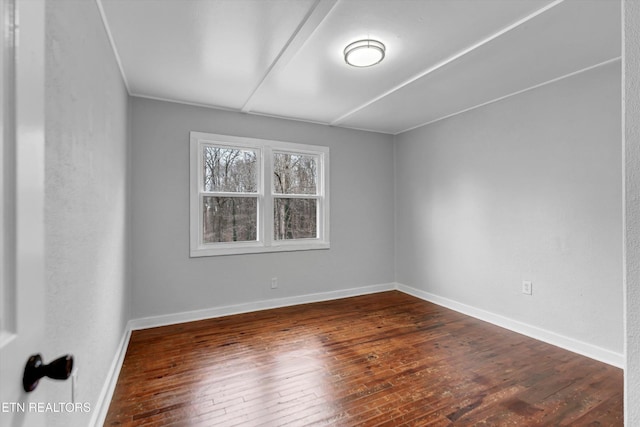 unfurnished room featuring baseboards and dark wood-type flooring