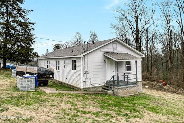 rear view of house with a shingled roof and a yard