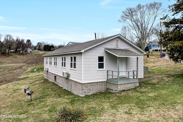 rear view of house featuring a yard, central AC, and a shingled roof