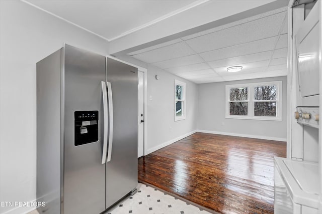 kitchen featuring wood-type flooring, baseboards, a drop ceiling, and stainless steel fridge with ice dispenser