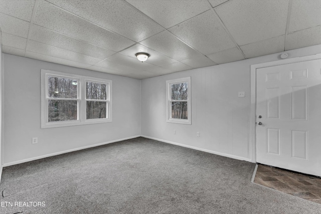 empty room with carpet floors, baseboards, and a paneled ceiling