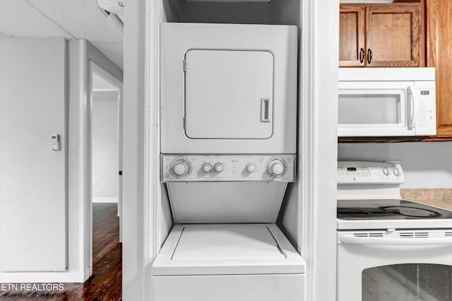 laundry room featuring baseboards, stacked washer and dryer, and wood finished floors