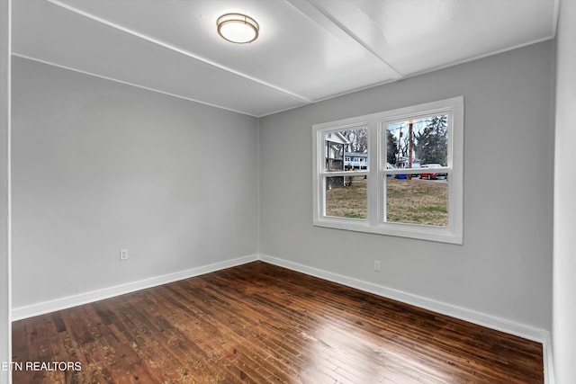 spare room featuring baseboards and dark wood-style flooring