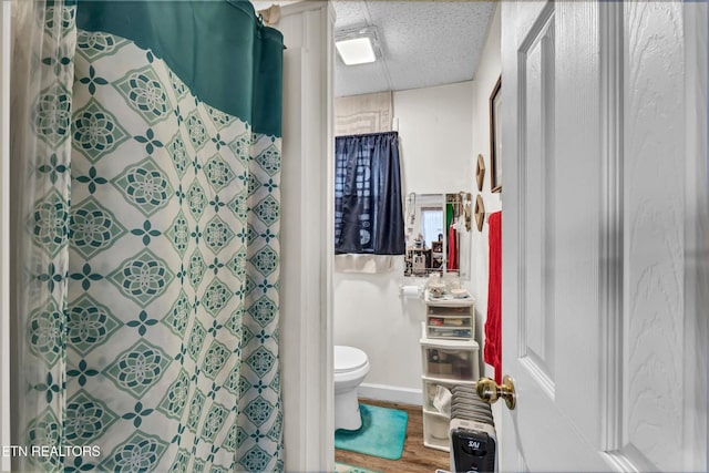 full bathroom featuring baseboards, toilet, wood finished floors, and a shower with shower curtain