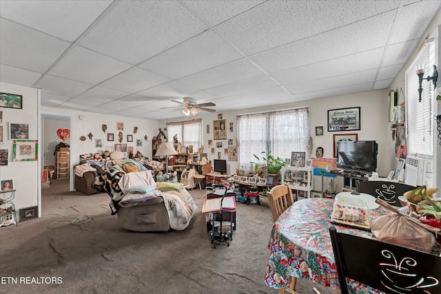 carpeted living room featuring ceiling fan and a drop ceiling