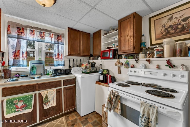 kitchen featuring open shelves, brown cabinetry, washer / clothes dryer, a drop ceiling, and white electric stove