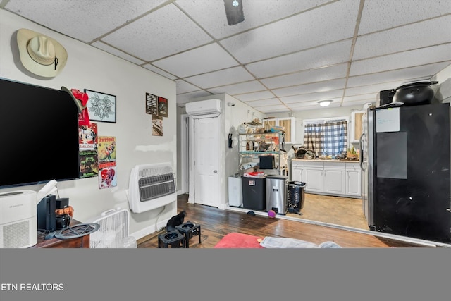 565567 W Outer Dr, Oak Ridge, TN 37830 - interior space featuring freestanding refrigerator, heating unit, wood finished floors, a paneled ceiling, and a wall unit AC