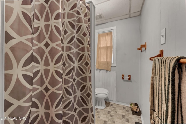 bathroom with a paneled ceiling, toilet, and a shower with curtain