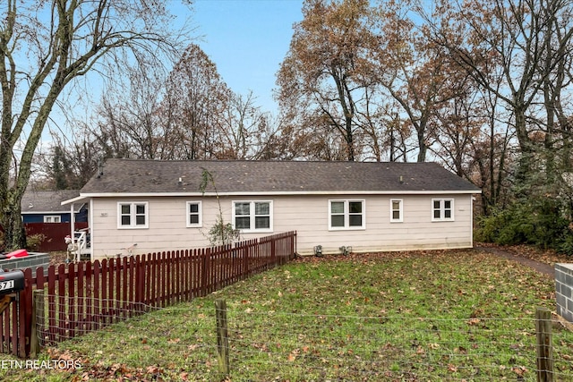 back of house featuring a lawn and fence