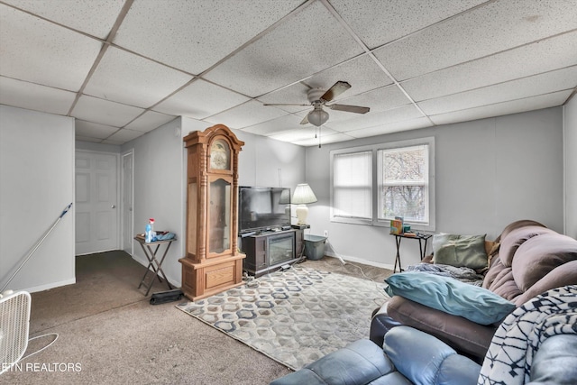 living area featuring carpet floors, a ceiling fan, baseboards, and a drop ceiling
