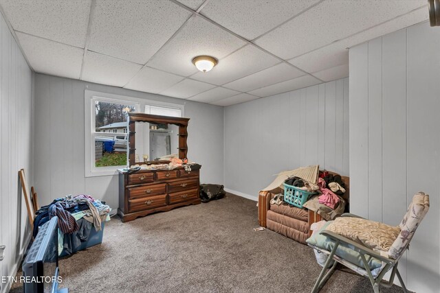 sitting room with wood walls, carpet flooring, and a drop ceiling