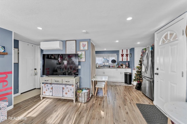 living area with recessed lighting, baseboards, an AC wall unit, and light wood finished floors
