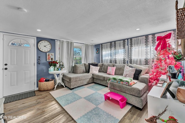 living area with recessed lighting, a textured ceiling, and wood finished floors