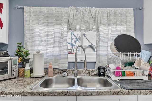 details featuring white cabinetry, a sink, and a toaster