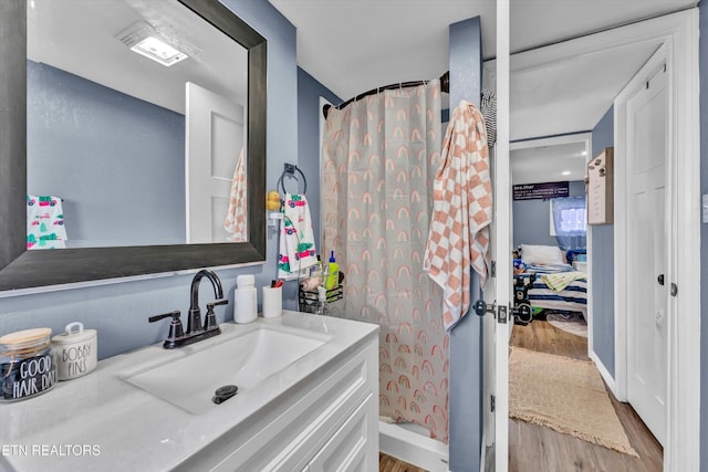 bathroom featuring curtained shower, wood finished floors, and vanity