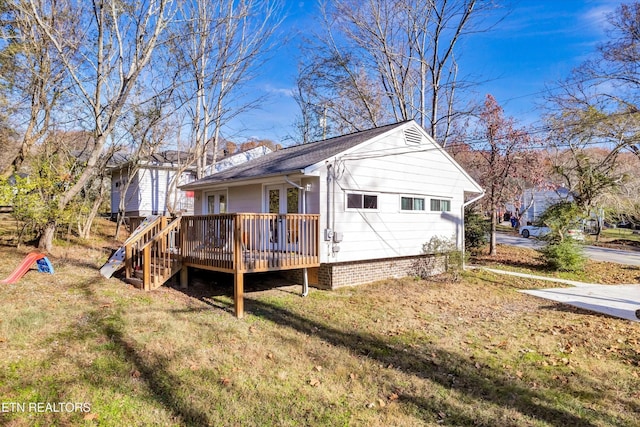 view of property exterior featuring a shingled roof, a yard, and a deck