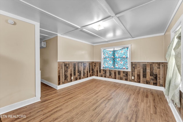 spare room featuring baseboards, coffered ceiling, wood finished floors, and wooden walls