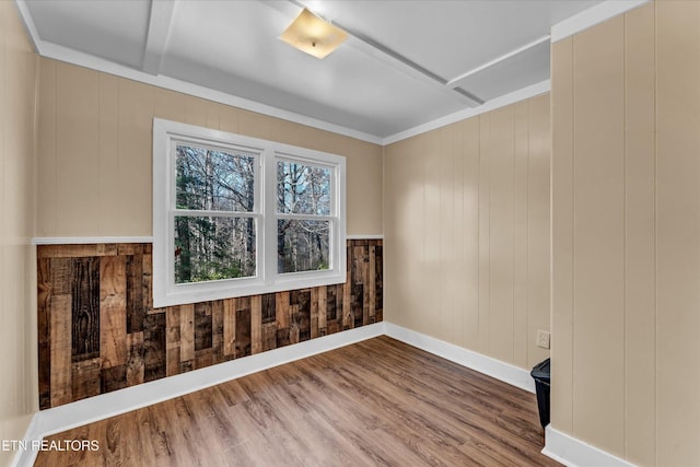 spare room with baseboards, wood finished floors, and wooden walls
