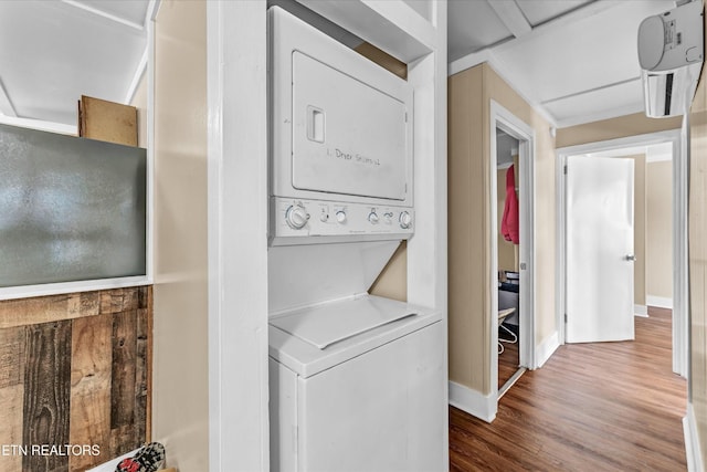 laundry room with baseboards, laundry area, stacked washer and dryer, and wood finished floors