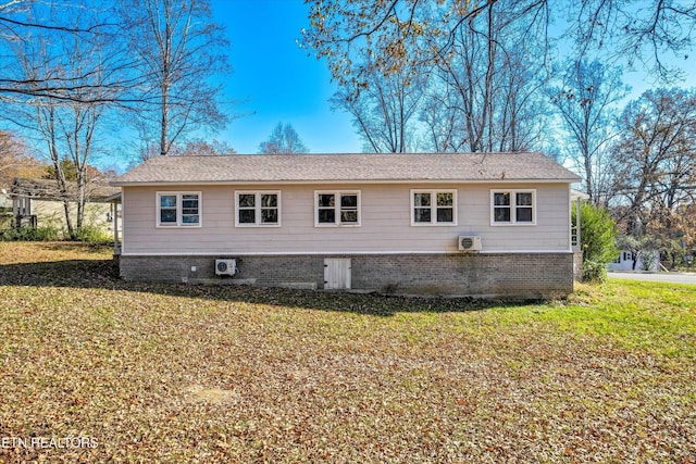 back of property with brick siding, ac unit, and a lawn