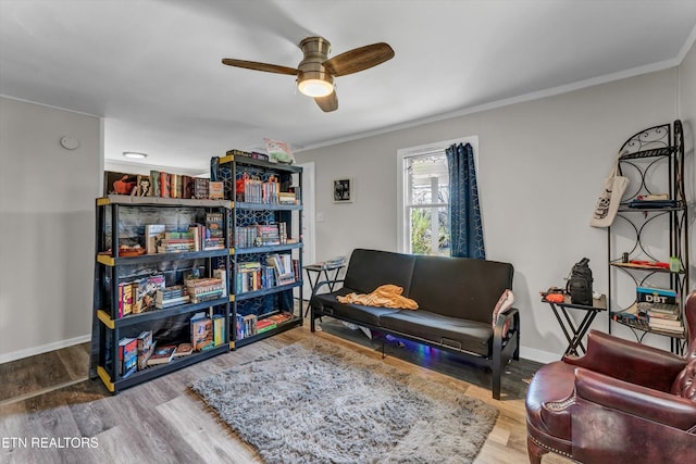 living area with crown molding, baseboards, a ceiling fan, and wood finished floors