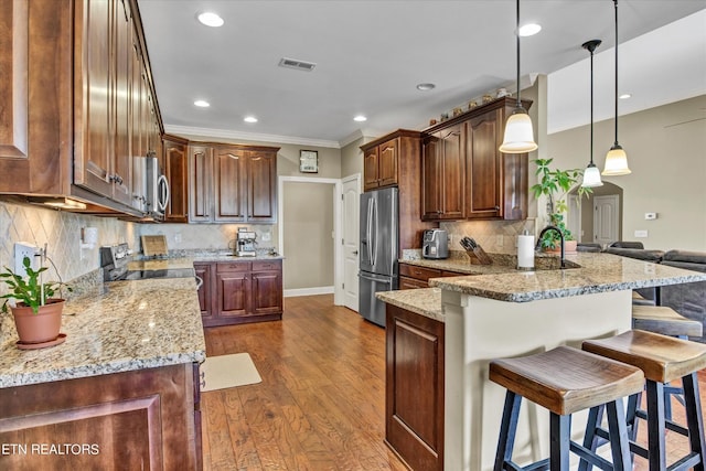 kitchen featuring a breakfast bar area, light stone countertops, a peninsula, stainless steel appliances, and dark wood-type flooring