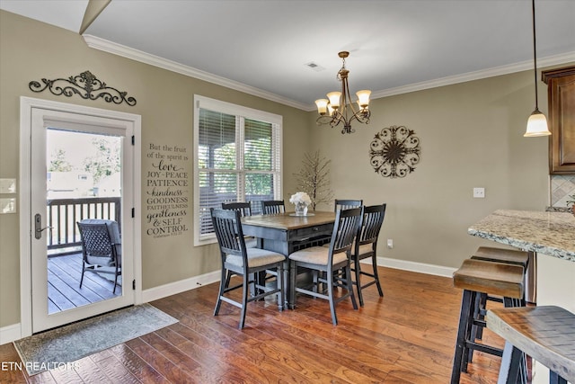 dining room featuring dark wood-type flooring, ornamental molding, baseboards, and an inviting chandelier