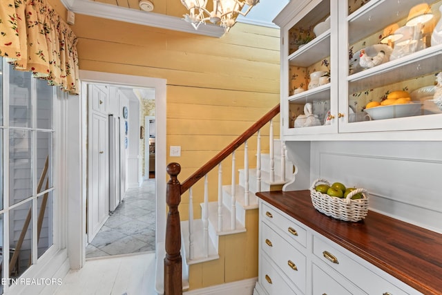 stairway with wood walls and an inviting chandelier