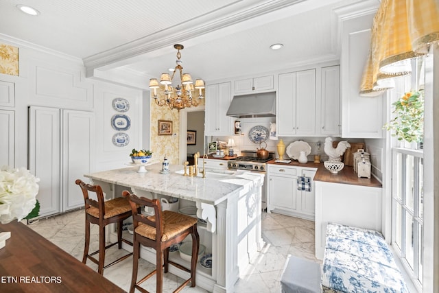 kitchen with gas range, crown molding, marble finish floor, a notable chandelier, and under cabinet range hood
