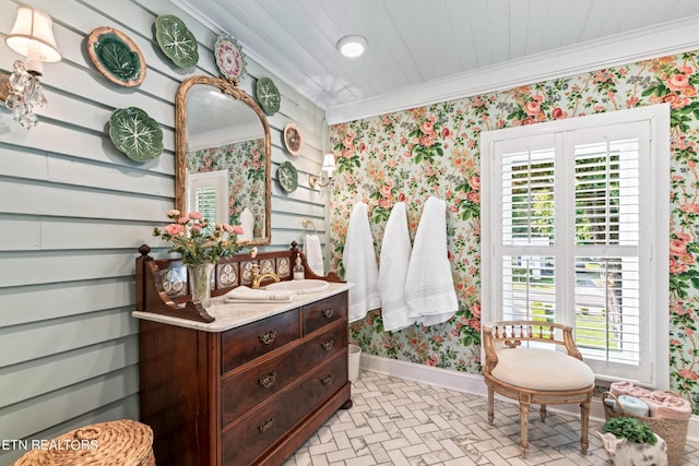 bathroom featuring vanity, ornamental molding, brick patterned floor, baseboards, and wallpapered walls