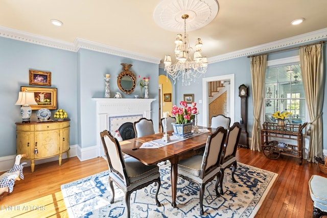 dining room featuring stairway, arched walkways, ornamental molding, and hardwood / wood-style flooring