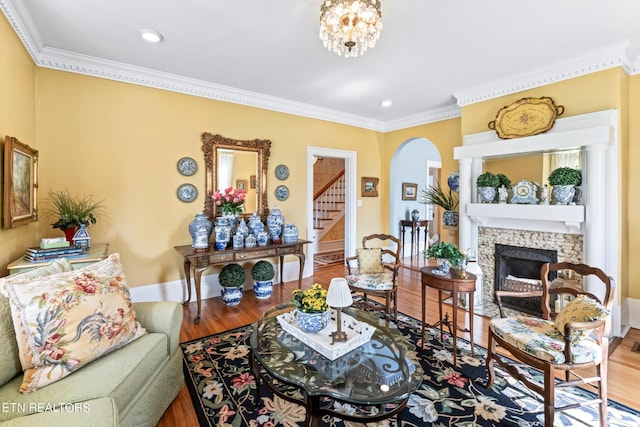 living room with a fireplace, baseboards, wood finished floors, ornamental molding, and stairway