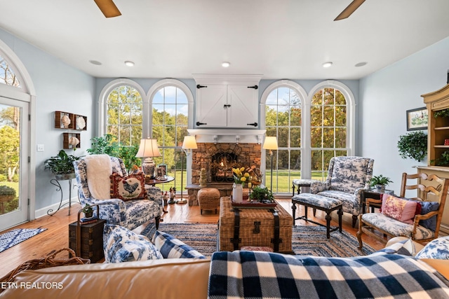 interior space with plenty of natural light, ceiling fan, wood finished floors, and a fireplace