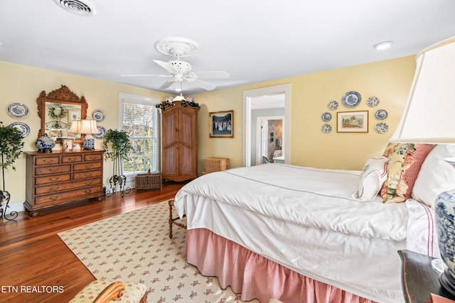 bedroom featuring ceiling fan, visible vents, and wood finished floors