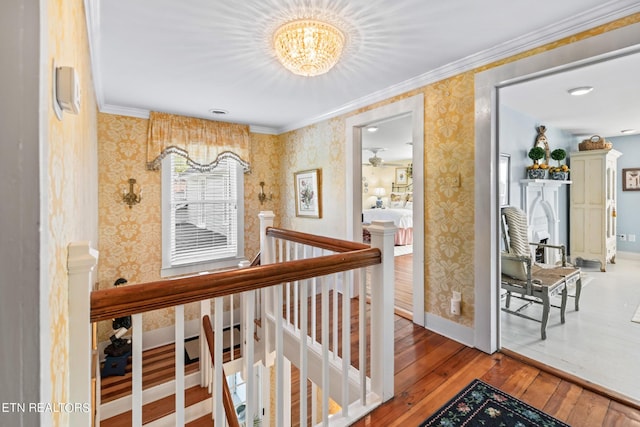 hallway featuring an upstairs landing, hardwood / wood-style flooring, baseboards, a notable chandelier, and wallpapered walls