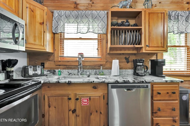 kitchen featuring a sink, plenty of natural light, light stone countertops, and stainless steel appliances
