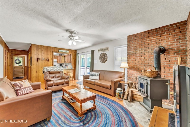 3178 N Clear Fork Rd, Sevierville, TN 37862 - living area featuring a wood stove, a textured ceiling, ceiling fan, and wood walls