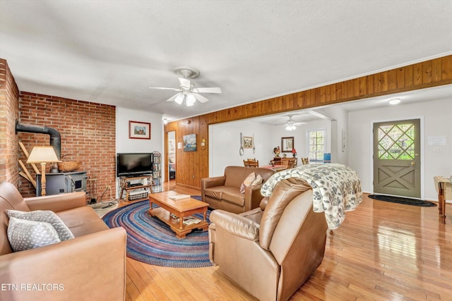 3178 N Clear Fork Rd, Sevierville, TN 37862 - living area with wooden walls, a ceiling fan, light wood-style flooring, and a wood stove