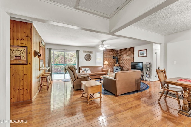 3178 N Clear Fork Rd, Sevierville, TN 37862 - living room with a wood stove, a textured ceiling, wood walls, and light wood-style flooring