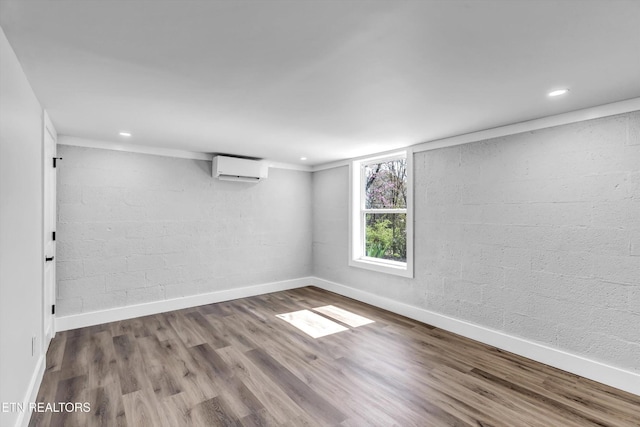 unfurnished room featuring baseboards, a wall unit AC, recessed lighting, and wood finished floors